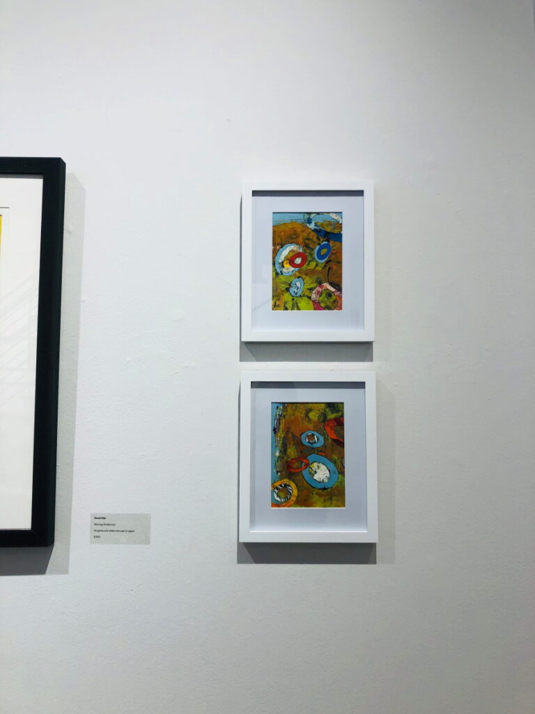 This is a photograph of two paintings on display at the A2AC Gallery in Ann Arbor, Michigan.