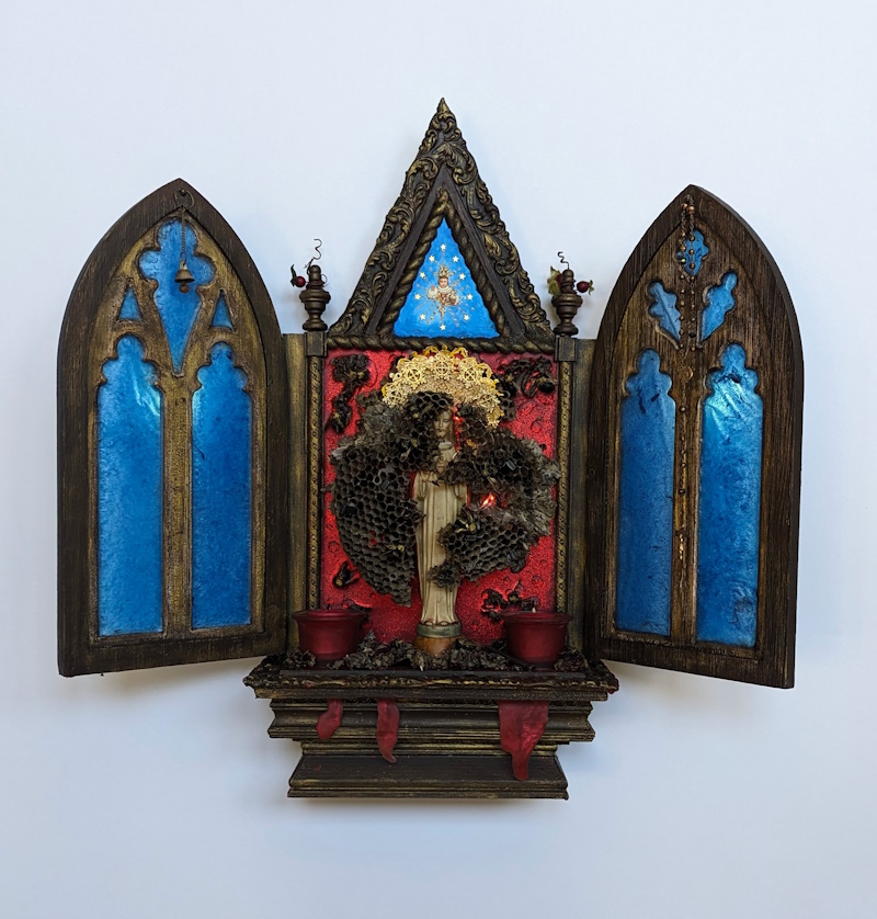 An intricately crafted Iconostasis Shrine featuring a central Christ figure illuminated with red LED light, surrounded by deep blue resin windows symbolizing the spiritual realm, and bees’ combs wrapped around the figure, highlighting themes of faith and creativity.